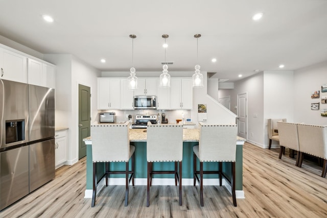 kitchen with appliances with stainless steel finishes, white cabinets, and light wood-style flooring