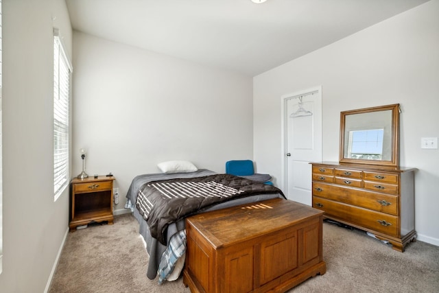 bedroom featuring light carpet, baseboards, and multiple windows