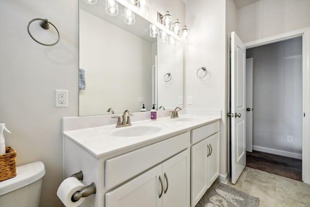 bathroom with toilet, double vanity, a sink, and tile patterned floors