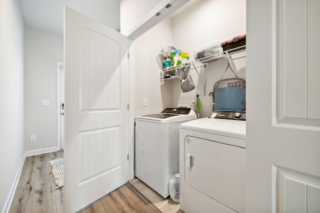 laundry room featuring laundry area, light wood-type flooring, washing machine and dryer, and baseboards