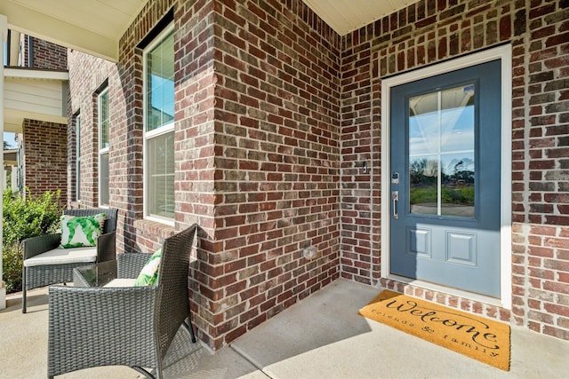 doorway to property with a porch and brick siding