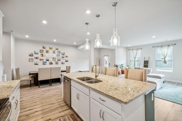 kitchen featuring light wood-style flooring, a sink, white cabinetry, open floor plan, and appliances with stainless steel finishes