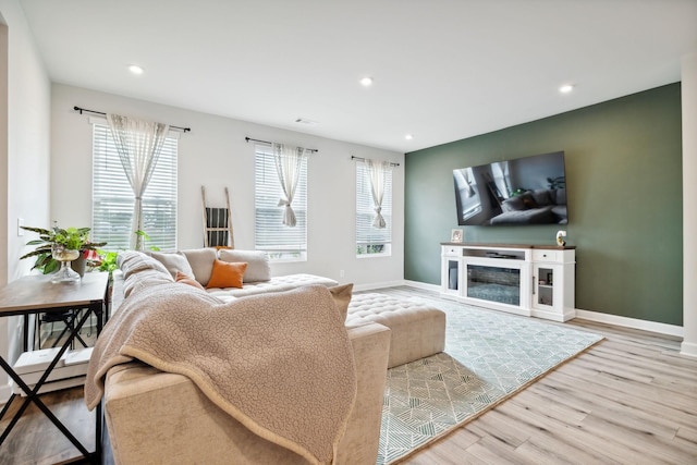 living area with recessed lighting, baseboards, wood finished floors, and a glass covered fireplace