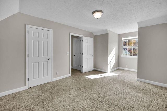 unfurnished bedroom with carpet flooring, a textured ceiling, and baseboards