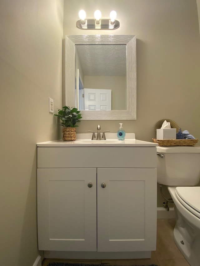 bathroom featuring tile patterned flooring, vanity, toilet, and baseboards