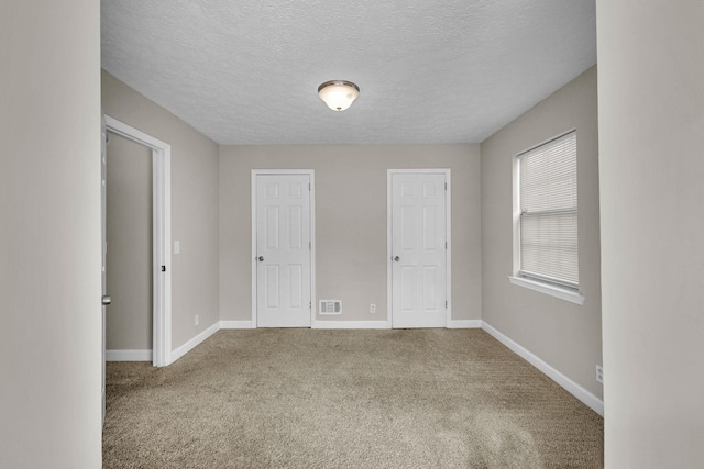 unfurnished bedroom with visible vents, a textured ceiling, baseboards, and carpet flooring