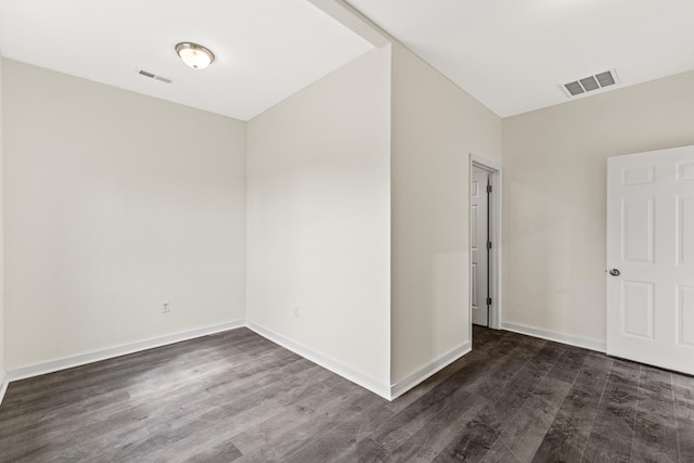 spare room featuring baseboards, visible vents, and dark wood-type flooring