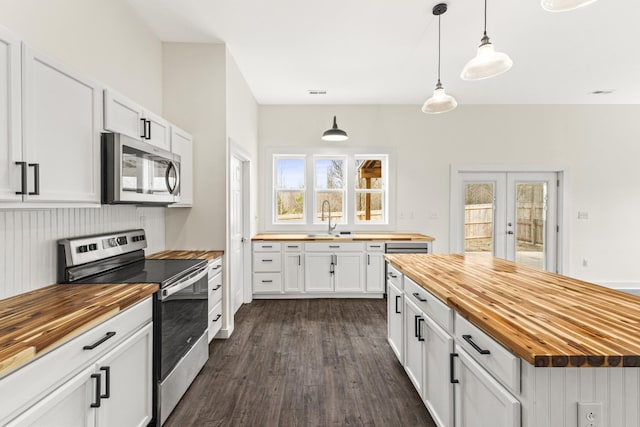 kitchen featuring butcher block counters, stainless steel appliances, and a sink