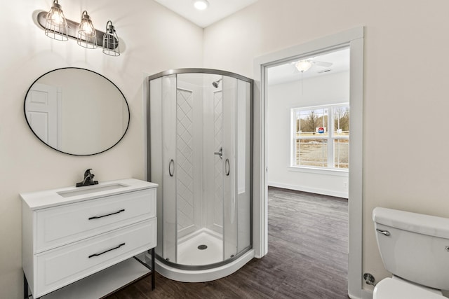 full bathroom with toilet, a stall shower, vanity, wood finished floors, and baseboards