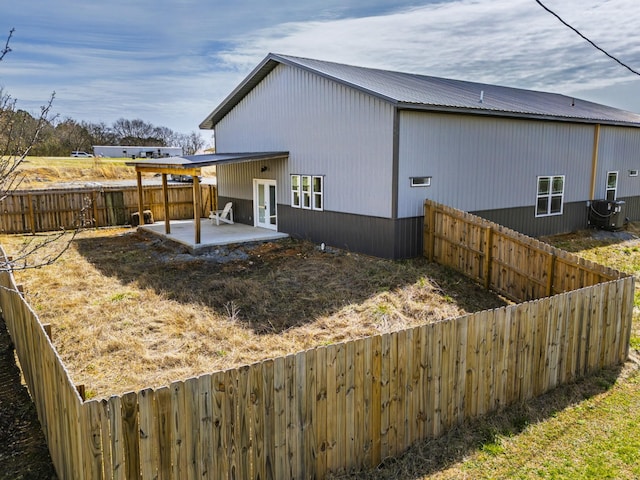 view of property exterior with a patio area, metal roof, and a fenced backyard