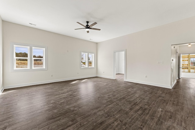 empty room with a ceiling fan, visible vents, dark wood finished floors, and baseboards