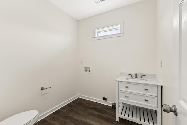 laundry area featuring visible vents, dark wood-type flooring, a sink, laundry area, and baseboards