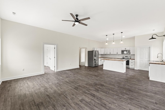 kitchen featuring a sink, white cabinetry, open floor plan, appliances with stainless steel finishes, and a center island