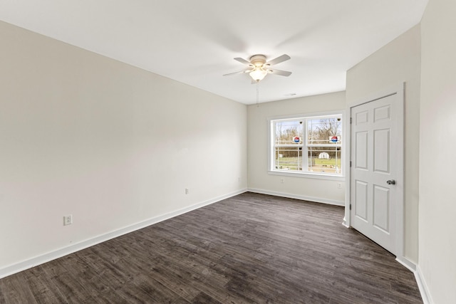 empty room featuring ceiling fan, baseboards, and dark wood finished floors