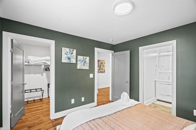 bedroom with wood finished floors, connected bathroom, and baseboards