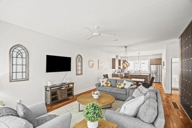 living area with light wood-type flooring, ceiling fan, visible vents, and baseboards