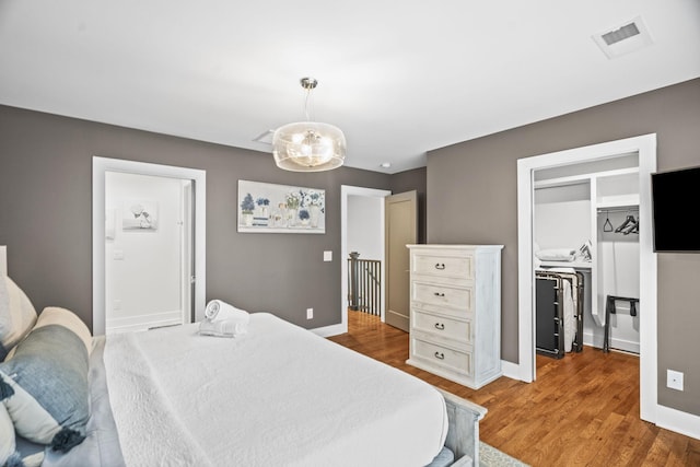 bedroom with wood finished floors, visible vents, and baseboards