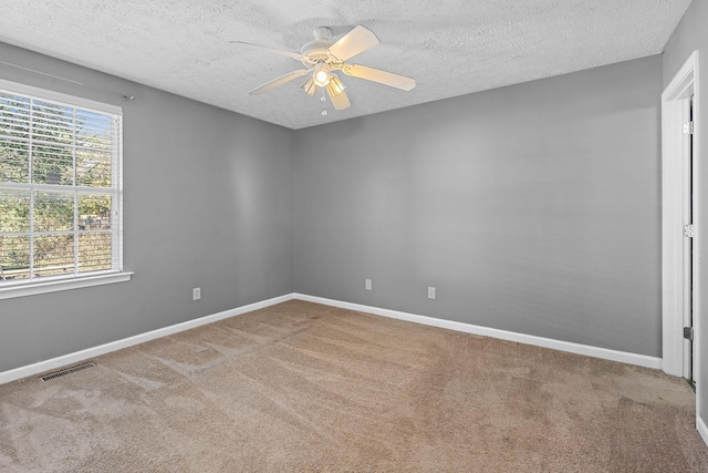 carpeted spare room featuring ceiling fan, a textured ceiling, visible vents, and baseboards