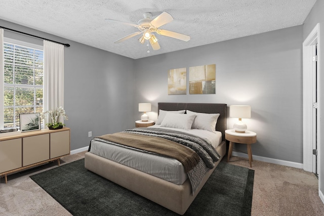 carpeted bedroom with a textured ceiling, a ceiling fan, and baseboards