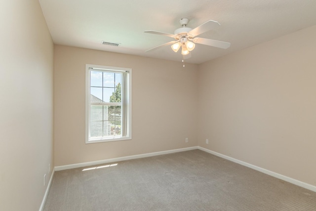 empty room featuring light carpet, ceiling fan, visible vents, and baseboards