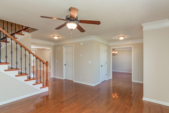 interior space featuring ceiling fan with notable chandelier, wood finished floors, baseboards, stairs, and ornamental molding