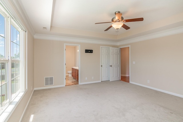 unfurnished bedroom with a raised ceiling, visible vents, light carpet, and baseboards