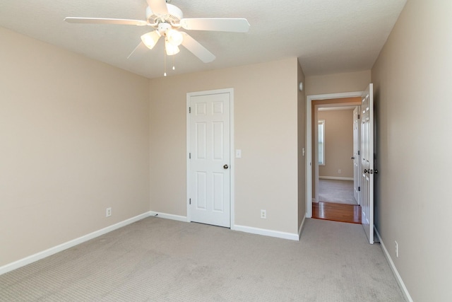 unfurnished bedroom with light colored carpet, ceiling fan, and baseboards