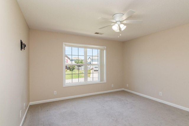 empty room with baseboards, visible vents, a ceiling fan, and light colored carpet