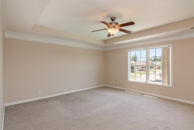 unfurnished room featuring carpet floors, baseboards, a raised ceiling, and ornamental molding