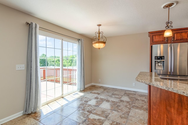 unfurnished dining area featuring a textured ceiling and baseboards