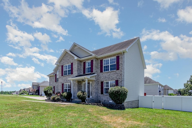 view of front of home with brick siding, a front lawn, fence, and a gate