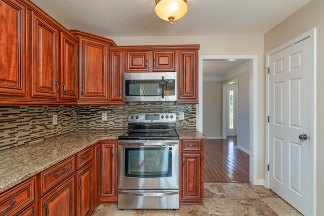 kitchen featuring tasteful backsplash, stone countertops, baseboards, appliances with stainless steel finishes, and crown molding