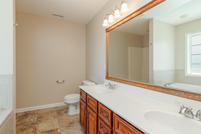 bathroom featuring toilet, a garden tub, double vanity, and a sink