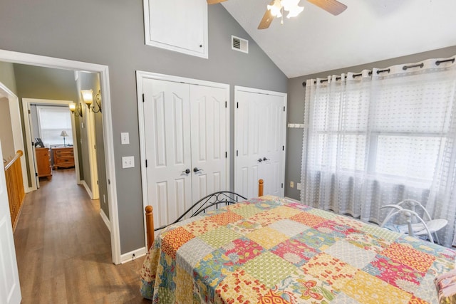 bedroom featuring ceiling fan, wood finished floors, visible vents, baseboards, and multiple closets