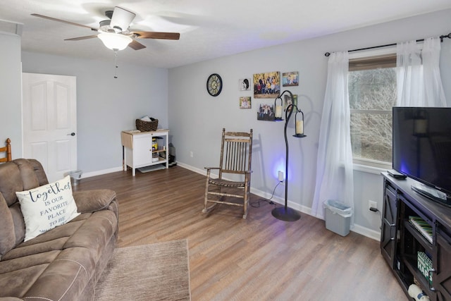 living area featuring a ceiling fan, a healthy amount of sunlight, baseboards, and wood finished floors