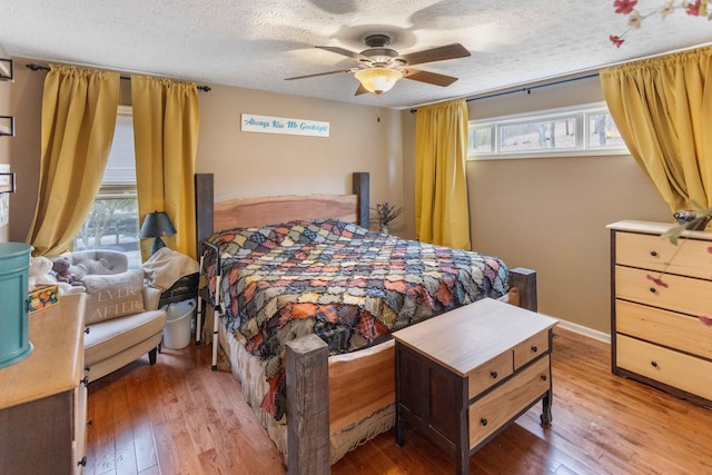 bedroom with a textured ceiling, ceiling fan, light wood finished floors, and baseboards