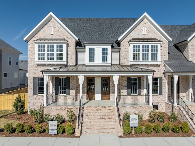 view of front of home featuring brick siding, covered porch, a standing seam roof, metal roof, and fence