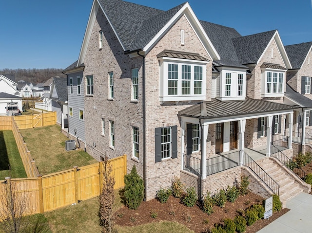 view of front of home featuring metal roof, central AC unit, covered porch, brick siding, and a standing seam roof