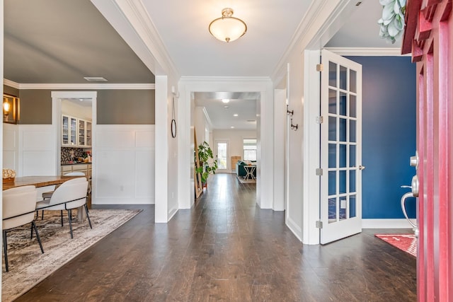 foyer featuring crown molding, a decorative wall, and wood finished floors