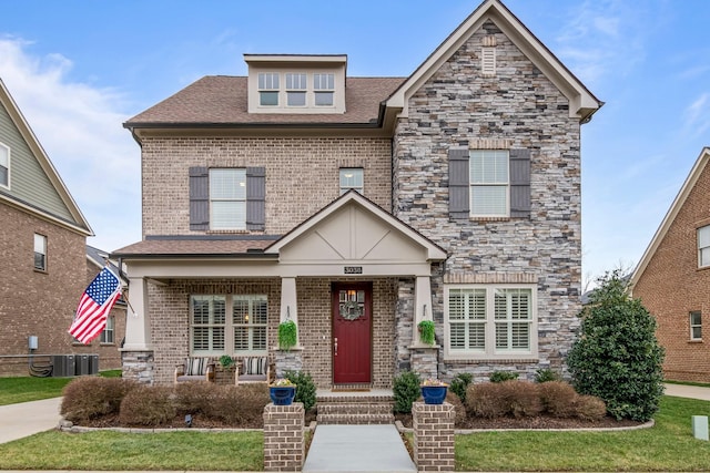 view of front of house featuring stone siding, a porch, roof with shingles, and brick siding