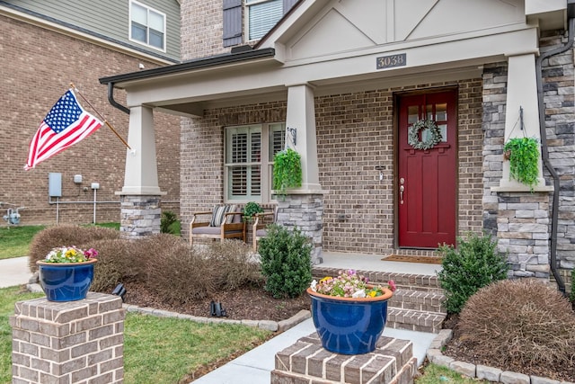 property entrance featuring a porch, stone siding, and brick siding