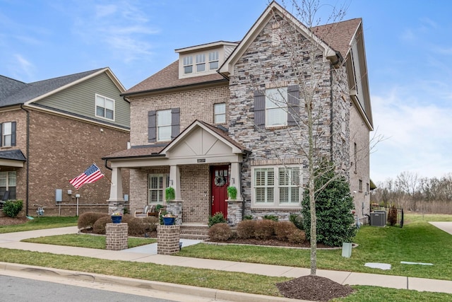 view of front of house with stone siding, a front yard, central AC, and brick siding