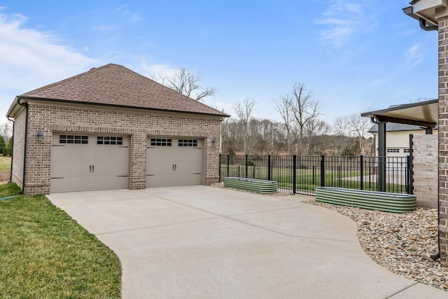 view of side of home featuring a detached garage, roof with shingles, fence, an outdoor structure, and brick siding