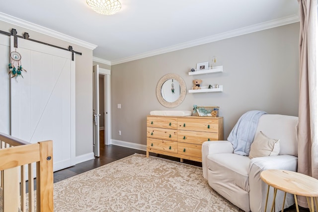 interior space with wood finished floors, crown molding, baseboards, and a barn door