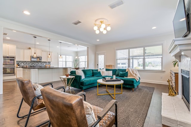 living room featuring a wealth of natural light, a brick fireplace, and visible vents