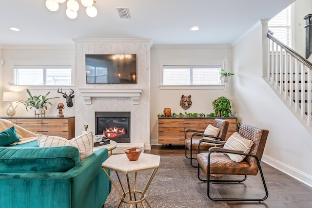 living area featuring plenty of natural light, a tiled fireplace, visible vents, and crown molding