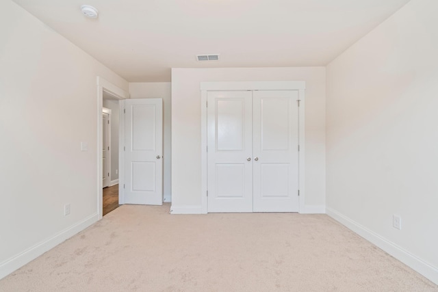 unfurnished bedroom with carpet floors, baseboards, visible vents, and a closet