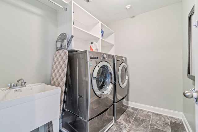 washroom with a sink, laundry area, washing machine and clothes dryer, and baseboards