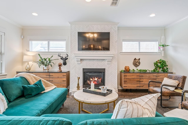 living area featuring ornamental molding, a fireplace, wood finished floors, and visible vents