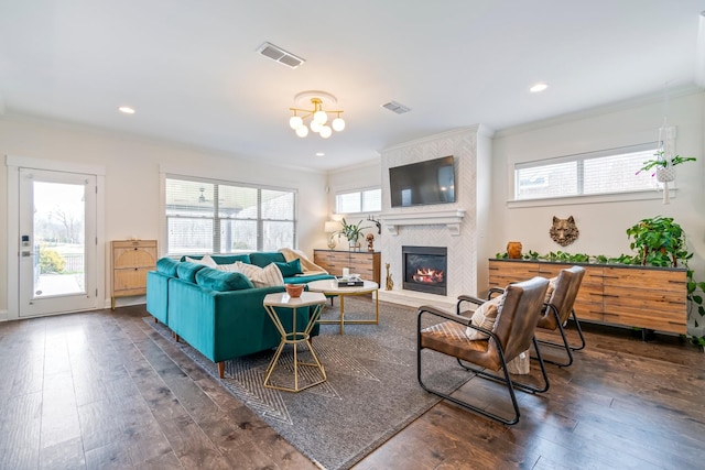 living room featuring a wealth of natural light, crown molding, visible vents, and hardwood / wood-style floors